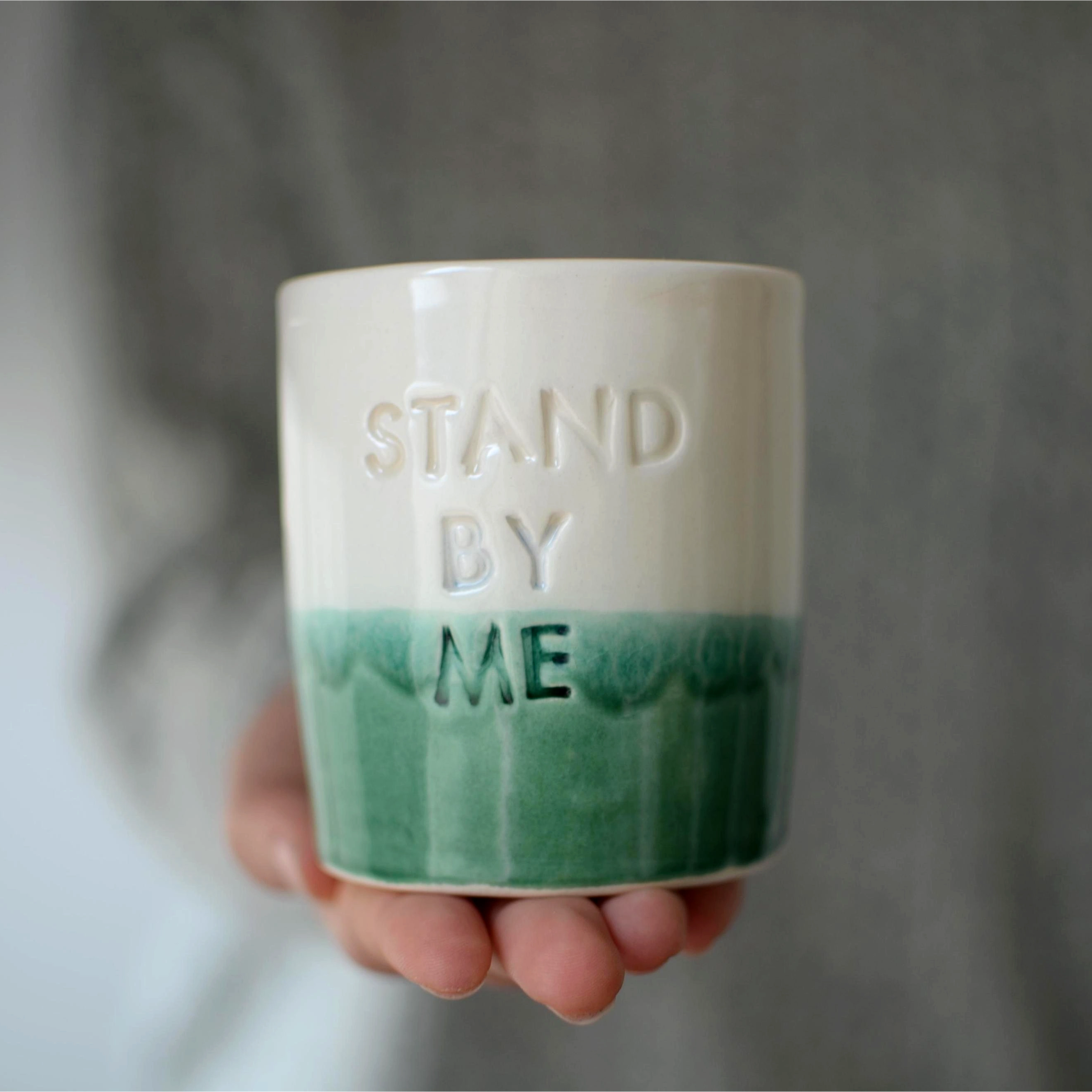 Manos sosteniendo vaso cerámica artesanal Stand By Me verde y blanco hecho a mano 230ml - Maia Artesanía Cerámica