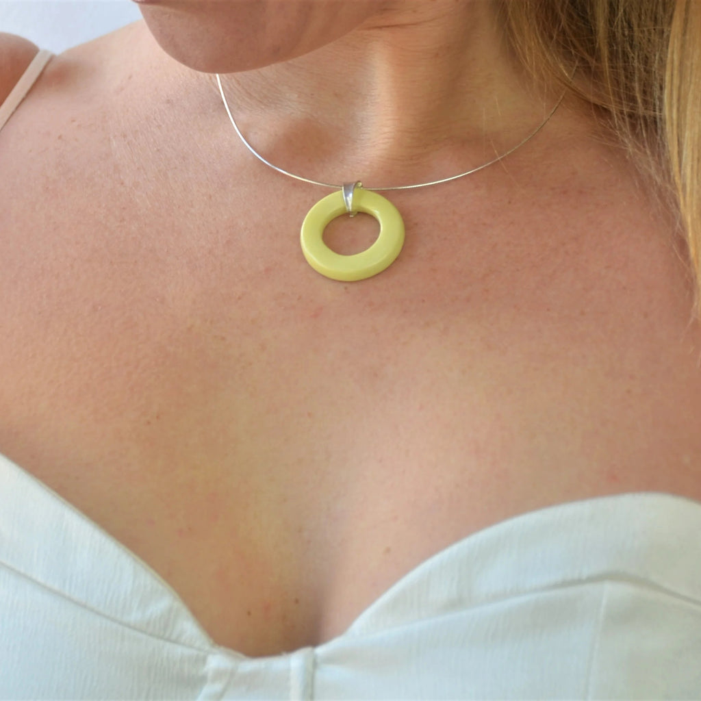 Colgante circular artesanal de cerámica amarillo con engarce de plata, hecho a mano por Maia Cerámica