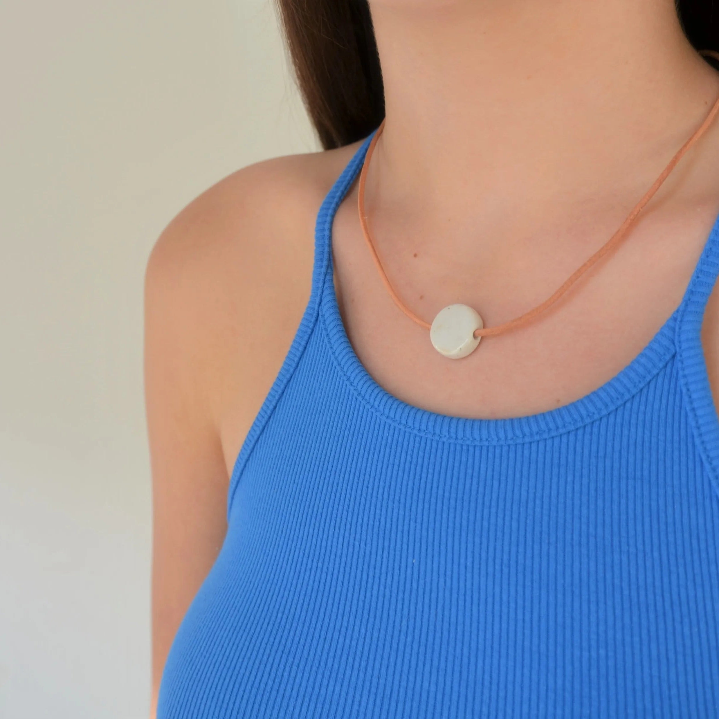 Collar de cerámica luna blanco sobre superficie natural, joyería artesanal única de Maia Cerámica