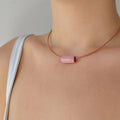 Collar artesanal de cerámica con diseño de tubo en tono rosa, cordón de cuero y cierre de plata de ley, hecho a mano por Maia Cerámica