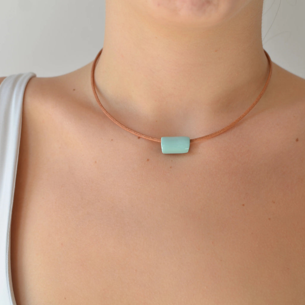 Collar artesanal de cerámica con diseño de tubo en tono verde menta y cordón de cuero con cierre de plata, hecho a mano por Maia Cerámica