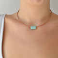 Collar artesanal de cerámica con diseño de tubo en tono verde menta y cordón de cuero con cierre de plata, hecho a mano por Maia Cerámica