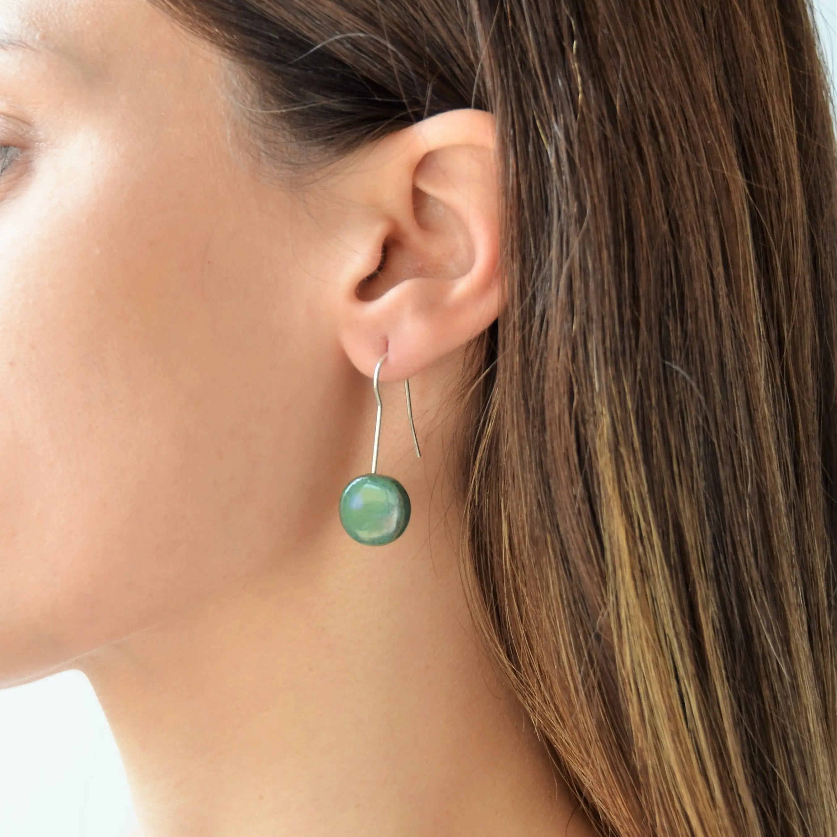 Pendientes artesanales de cerámica luna verde azulado con enganche de plata, hecho a mano por Maia Cerámica