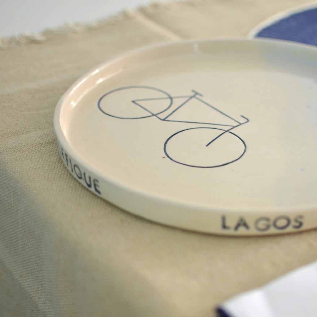 Detalle bicicleta y nombres de lugares en plato cerámica artesanal celeste hecho a mano - Maia Artesanía Cerámica