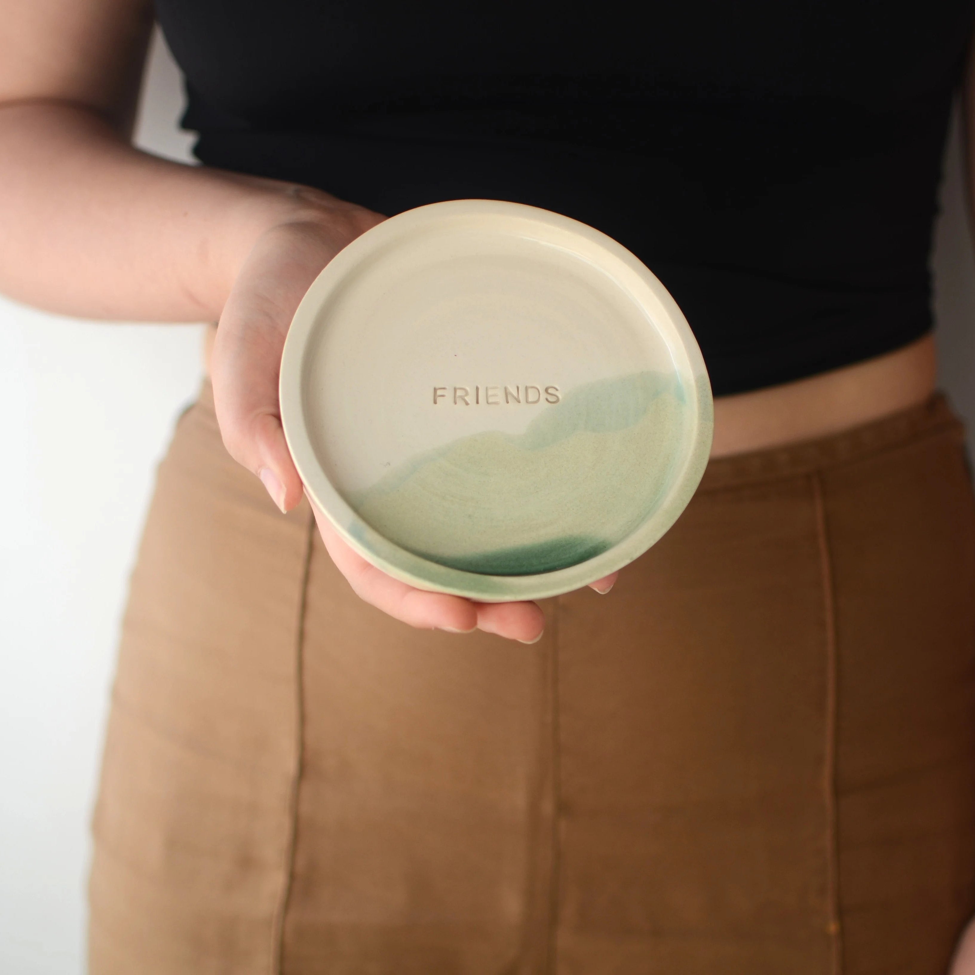 Mano sosteniendo plato cerámica artesanal Friends blanco y verde hecho a mano 13cm - Maia Artesanía CerámicaCerámica