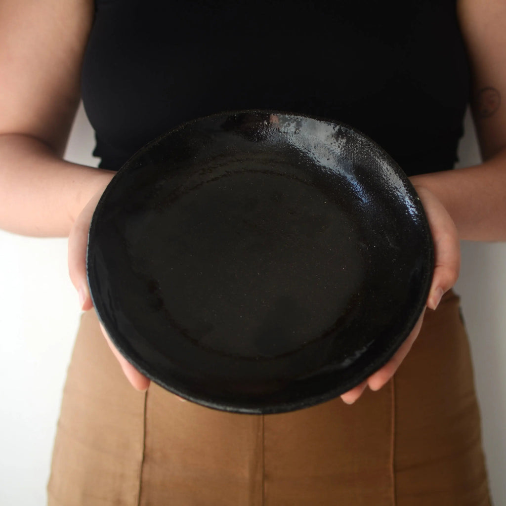 Detalle de plato de cerámica negra artesanal hecho a mano, acabado mate y textura natural única